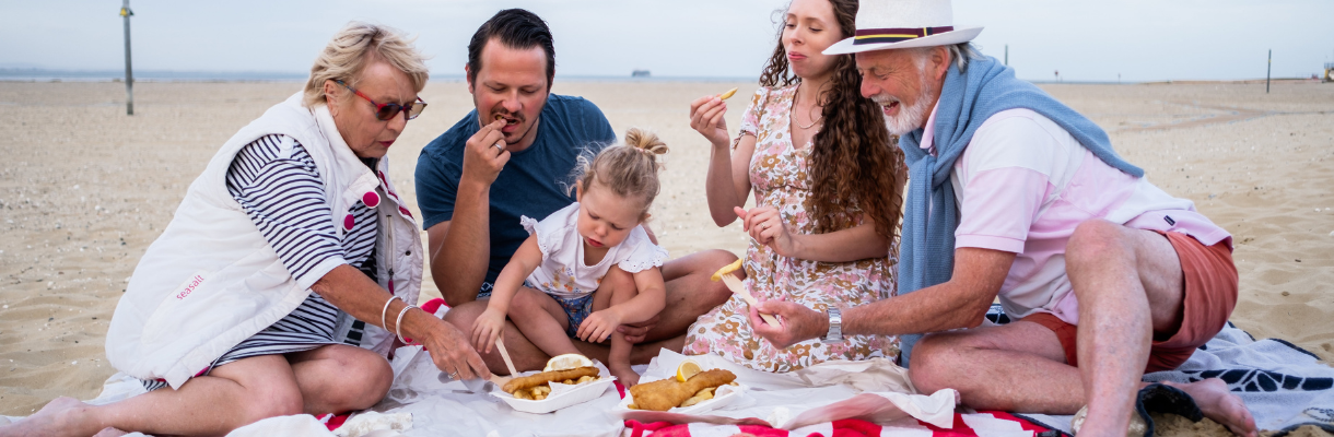 Family sat of Ryde beach eating Fish and Chips